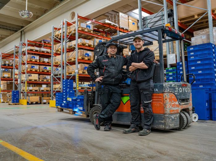 Zwei Avant Lager Mitarbeiter stehen vor einem Gabelstapler in einem Lagerhaus