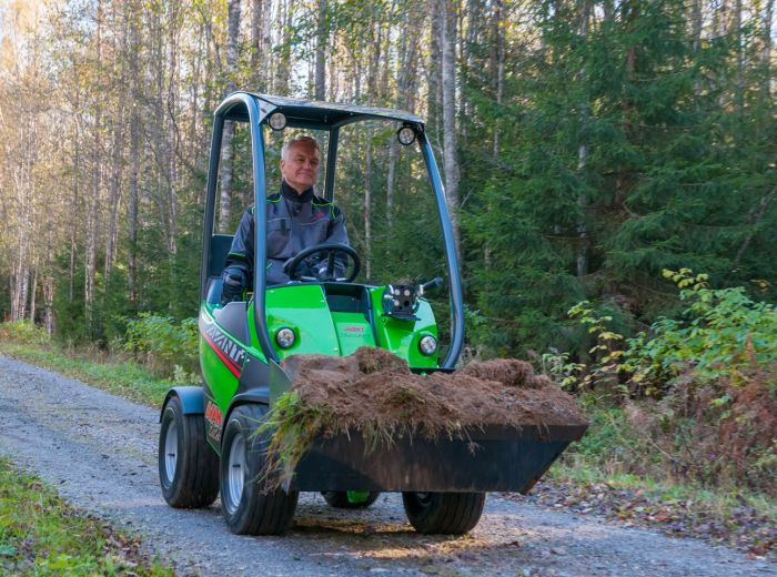 Ein Mann fährt einen grünen Avant-Traktor auf einem unbefestigten Weg