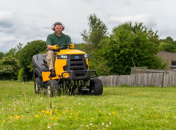 Ein Mann fährt mit einem gelben Kawasaki Aufsitzmäher durch ein weitläufiges Feld