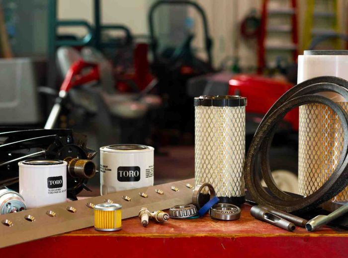 Auf einem Tisch liegen diverse Artikel, wie ein Schlauch, ein Filter und andere Werkzeuge der Service Toro Werkbank