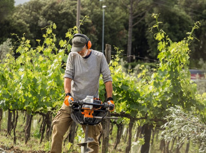 Ein Mann nutzt einen benzinbetriebenen Rasentrimmer von Stihl zur Pflege seines Gartens