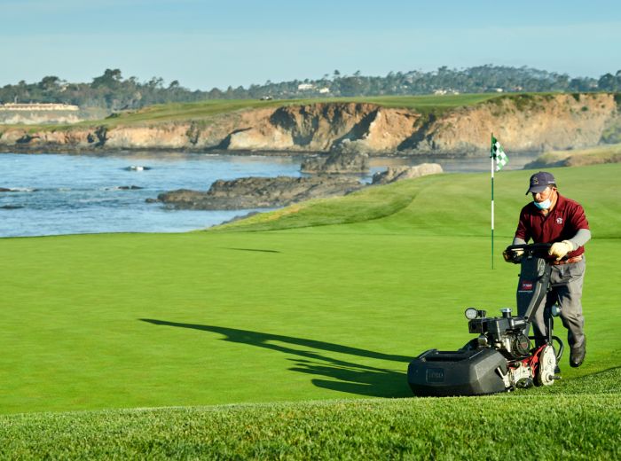 Mann mit Toro Rasenmäher, der den Rasen auf einem Golfplatz pflegt
